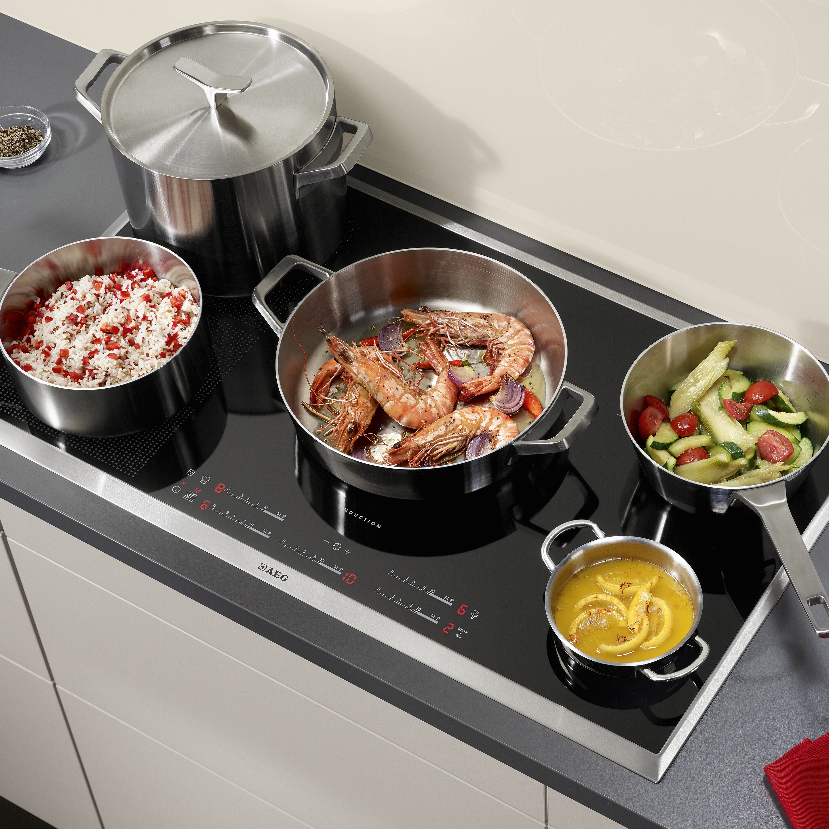 Différents plats en train de cuire sur une table de cuisson à induction AEG